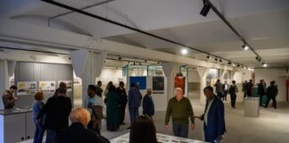 diverse persone affollano la sala espositiva della mostra dedicata a Mogadiscio al magazzino 26 di trieste