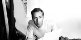 un giovanissimo renato balestra nel suo laboratorio circondato da stoffe e disegni