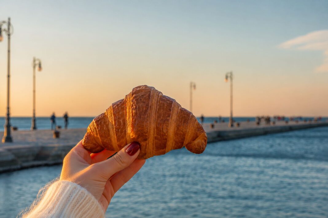 ragazza che tiene in mano un cornetto e sullo sfondo il Molo Audace di Trieste