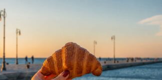 ragazza che tiene in mano un cornetto e sullo sfondo il Molo Audace di Trieste