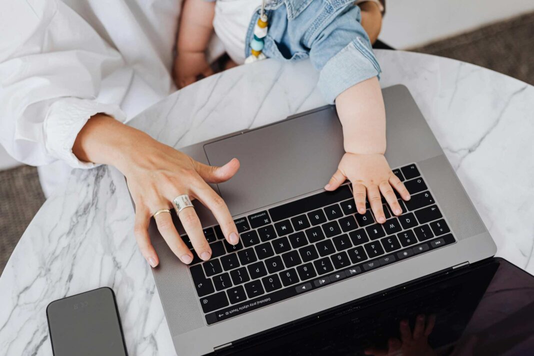 Madre digita al pc e tiene in braccio il figlio: lavoro e maternità