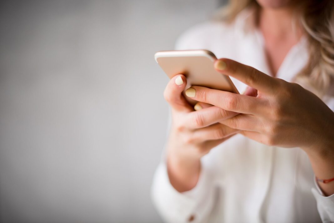 particolare di due mano di una donna che usano il cellulare