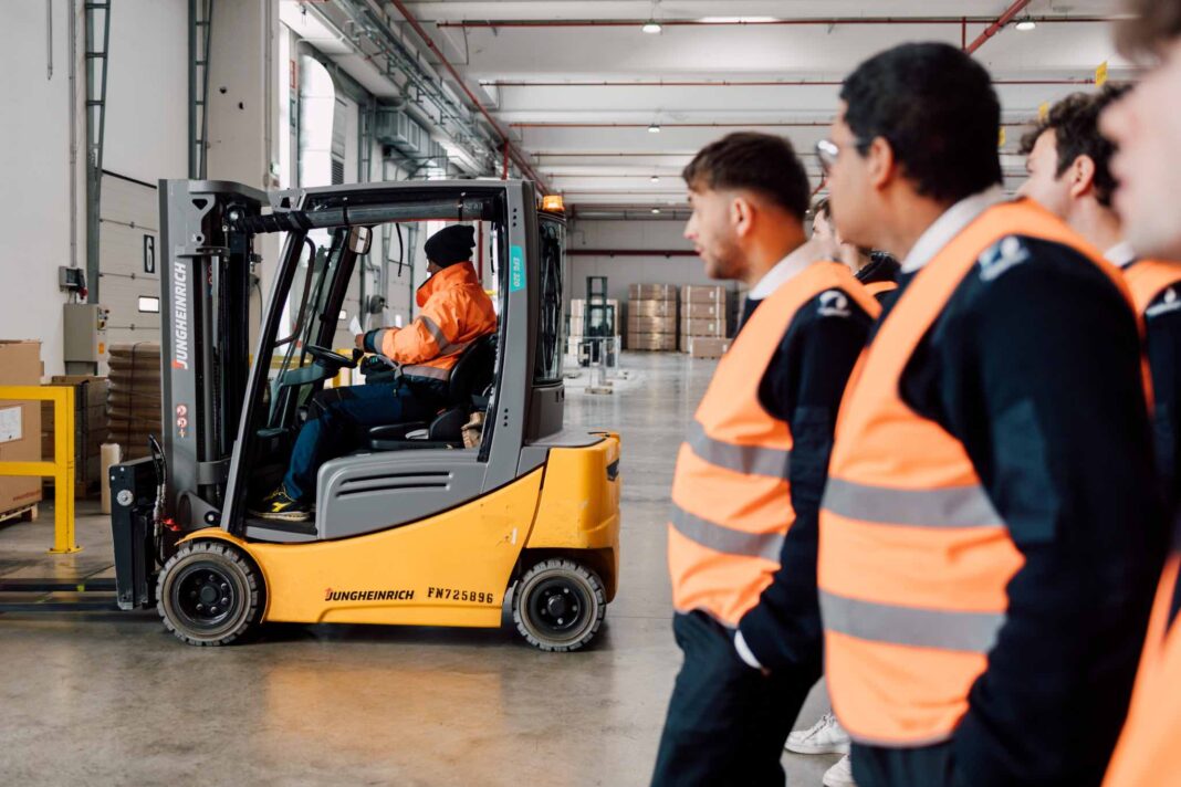 studenti dell'accademia nautica dell'adriatico durante una visita didattica in un magazzino di logistica. un operatore muove un muletto