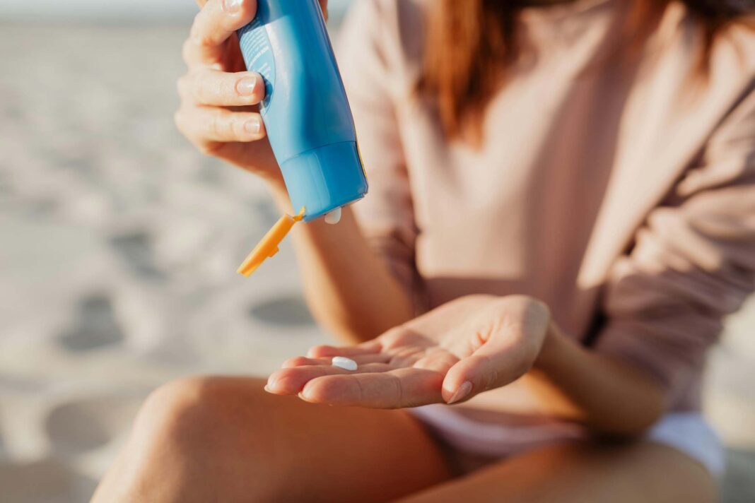 Ragazza in spiaggia applica la crema solare sulla pelle