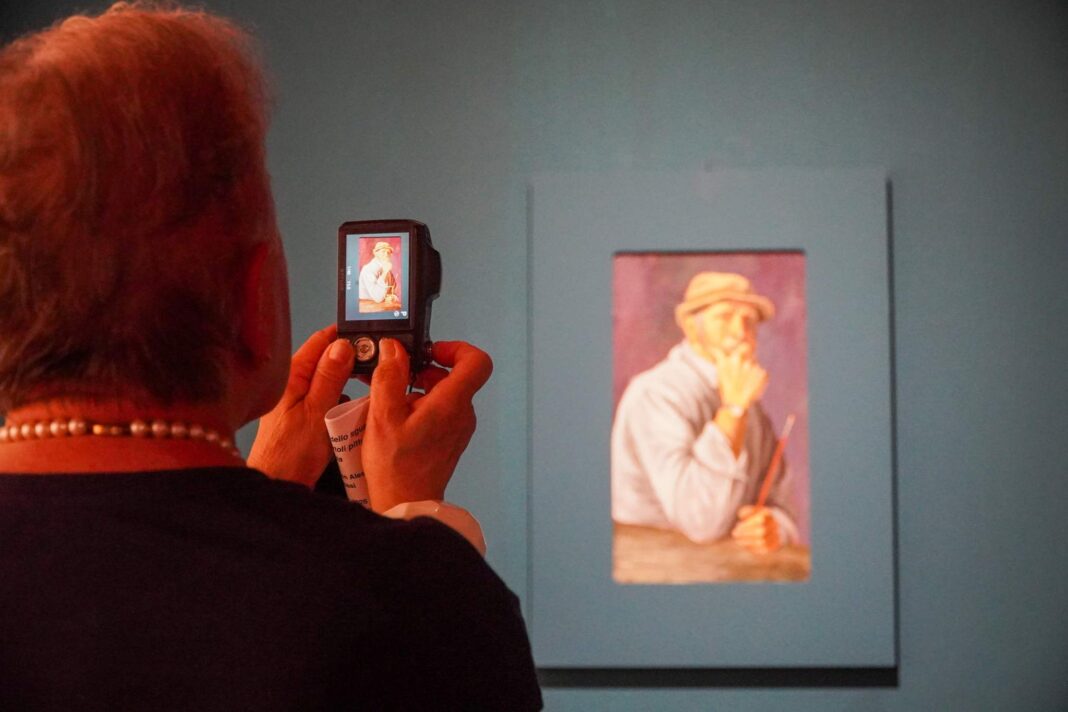 Signora fotografa un quadro alla mostra 