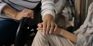 Più posti nelle case di riposo: il piano del Friuli Venezia Giulia per gli anziani non autosufficienti Caregiver tiene la mano a una paziente di una residenza per anziani