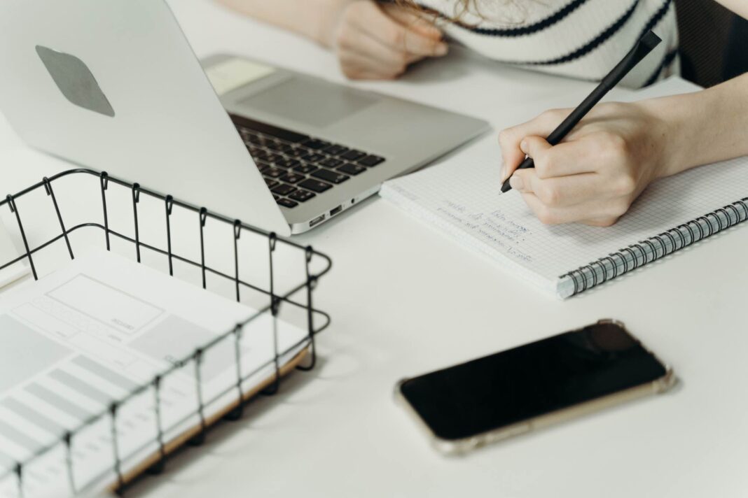 Studentessa prende appunti su un quaderno; app per lo studio