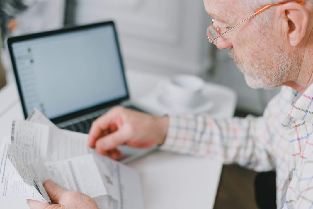 Anziano alla scrivania consulta dei documenti per il bonus pensioni