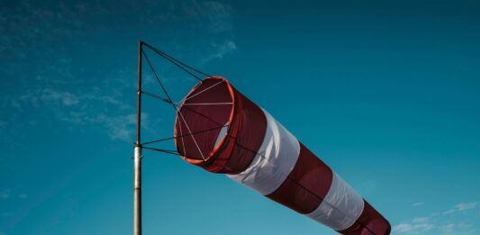 Una manica a vento rossa e bianca su un palo contro un cielo azzurro: immagine utilizzata per un articolo sulla qualità dell'aria in FVG
